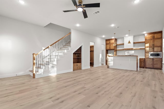 unfurnished living room featuring ceiling fan and light wood-type flooring