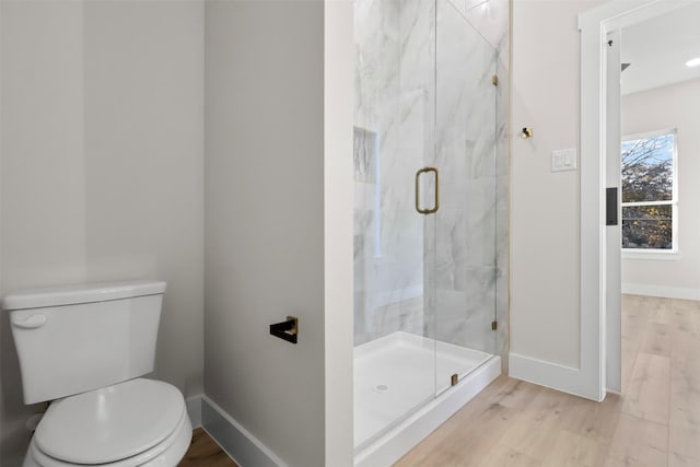 bathroom with a shower with door, hardwood / wood-style floors, and toilet