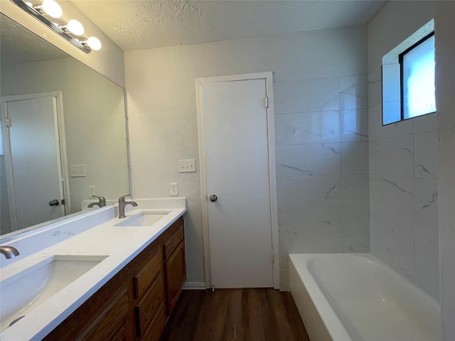 bathroom with vanity, wood-type flooring, a textured ceiling, and a bathing tub