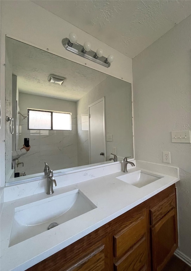 bathroom with vanity, a textured ceiling, and tiled shower