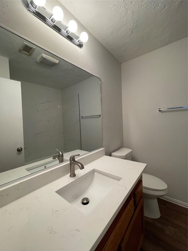 bathroom featuring hardwood / wood-style flooring, vanity, toilet, and a textured ceiling