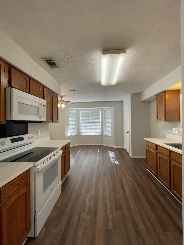 kitchen with white appliances, sink, ceiling fan, a textured ceiling, and dark hardwood / wood-style flooring