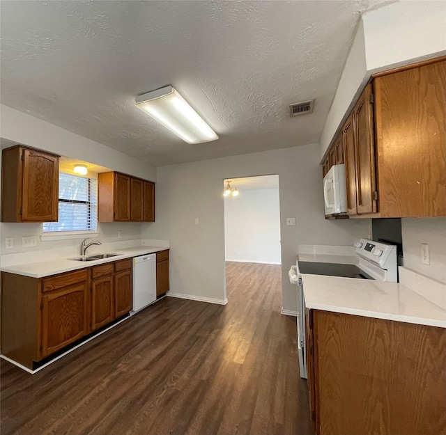 kitchen with sink, dark hardwood / wood-style flooring, a chandelier, a textured ceiling, and white appliances