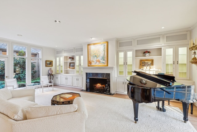 living room with light hardwood / wood-style floors, a premium fireplace, ornamental molding, and built in features