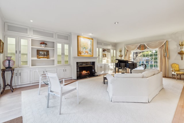 living room with built in shelves, light hardwood / wood-style floors, and a fireplace