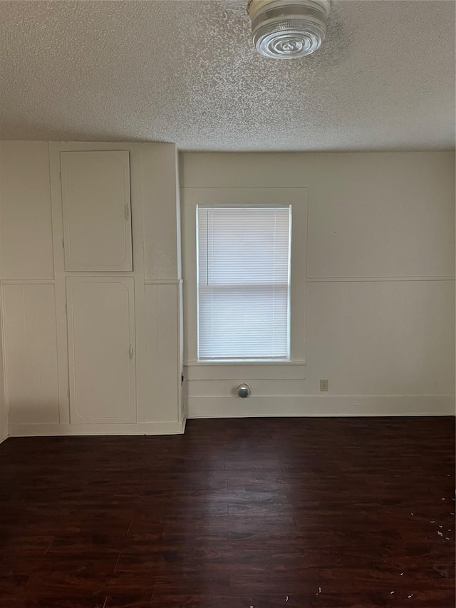 unfurnished room featuring dark hardwood / wood-style flooring and a textured ceiling