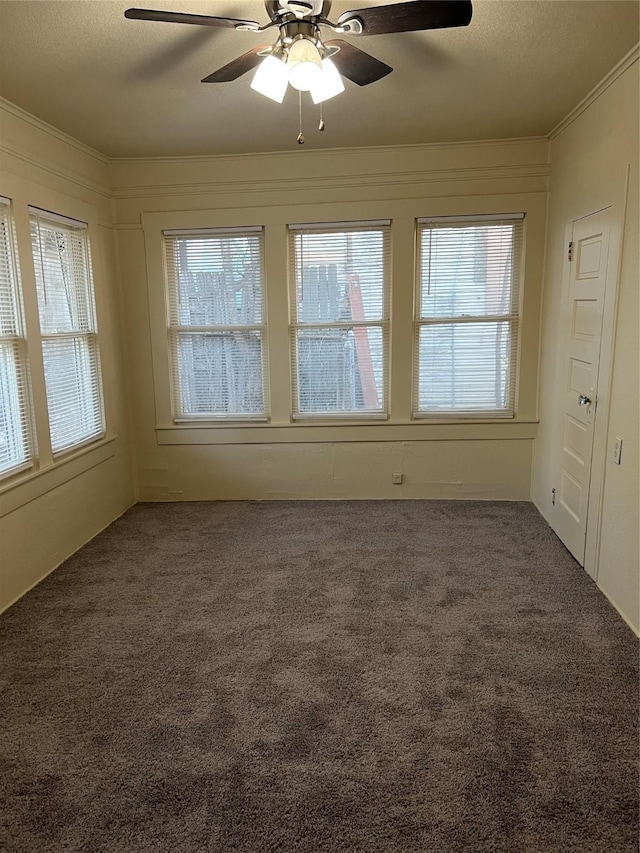 unfurnished room with a textured ceiling, dark carpet, ceiling fan, and ornamental molding