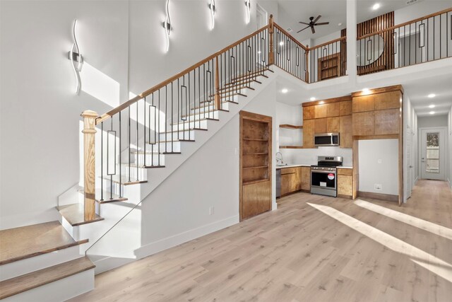 interior space with a towering ceiling, light hardwood / wood-style flooring, and ceiling fan