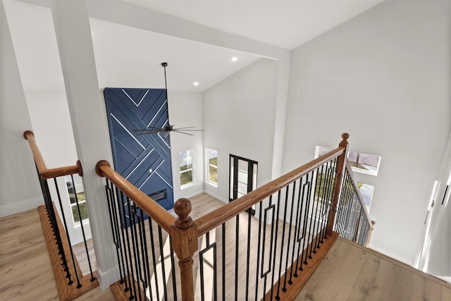 stairway with ceiling fan and wood-type flooring