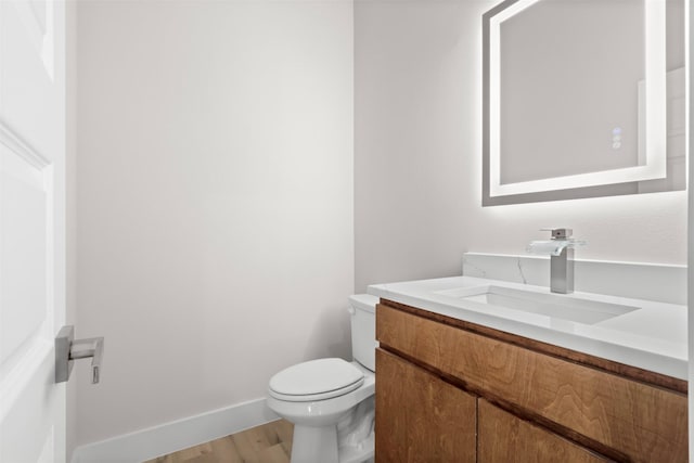 bathroom with wood-type flooring, vanity, and toilet