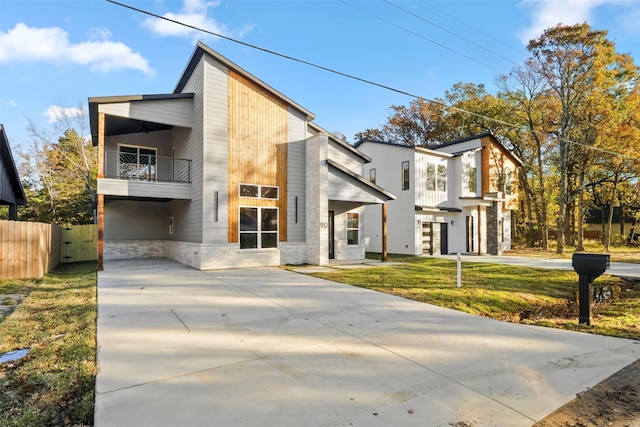 contemporary home with a balcony and a front yard