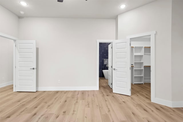 unfurnished bedroom with a spacious closet, a closet, and light hardwood / wood-style floors