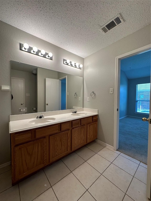 bathroom with tile patterned floors, vanity, and a textured ceiling