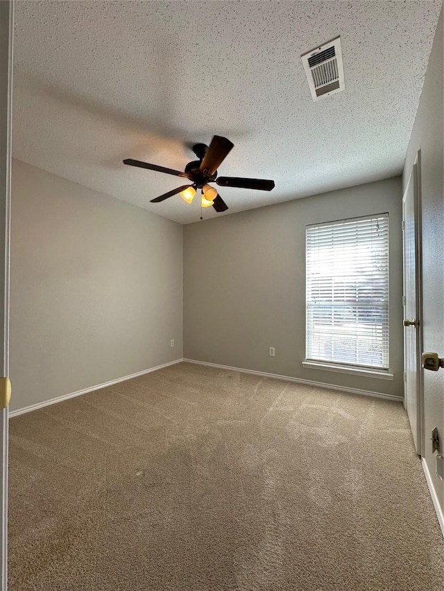 carpeted empty room featuring ceiling fan and a textured ceiling