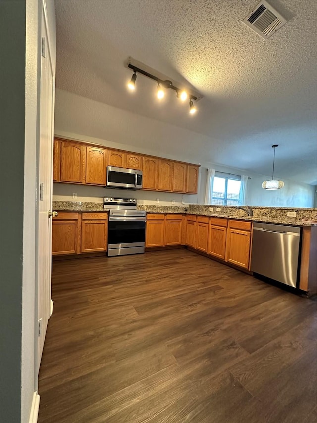 kitchen featuring dark hardwood / wood-style flooring, decorative light fixtures, a textured ceiling, and appliances with stainless steel finishes