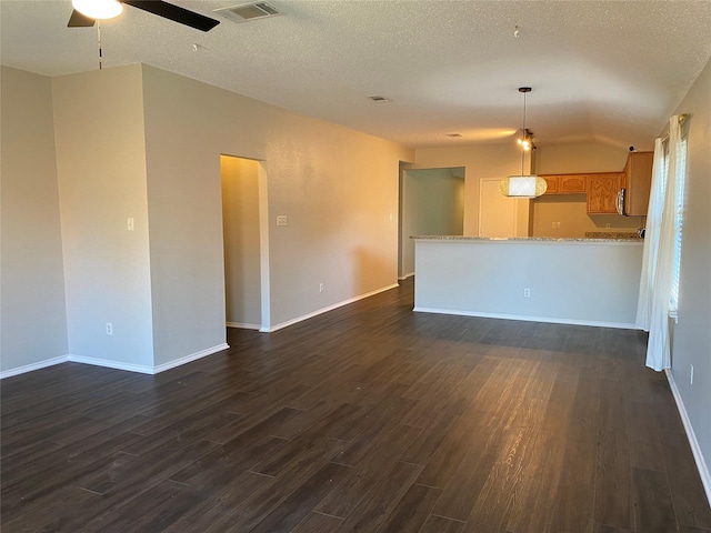 spare room featuring a textured ceiling, vaulted ceiling, dark hardwood / wood-style floors, and ceiling fan