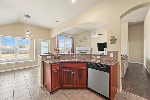 kitchen with dark stone counters, sink, stainless steel dishwasher, and vaulted ceiling