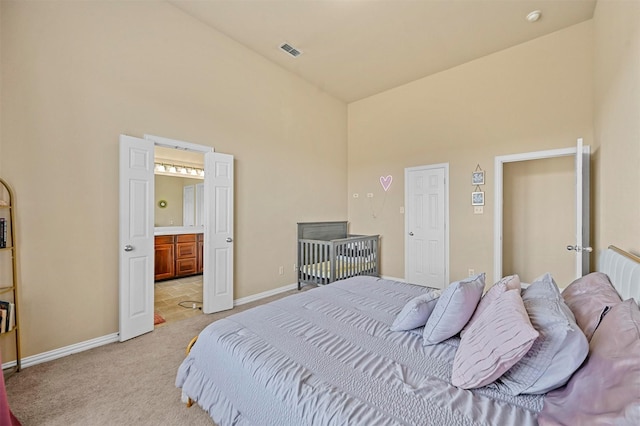 carpeted bedroom featuring connected bathroom and high vaulted ceiling