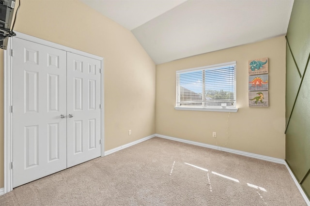 unfurnished bedroom featuring carpet flooring, a closet, and lofted ceiling