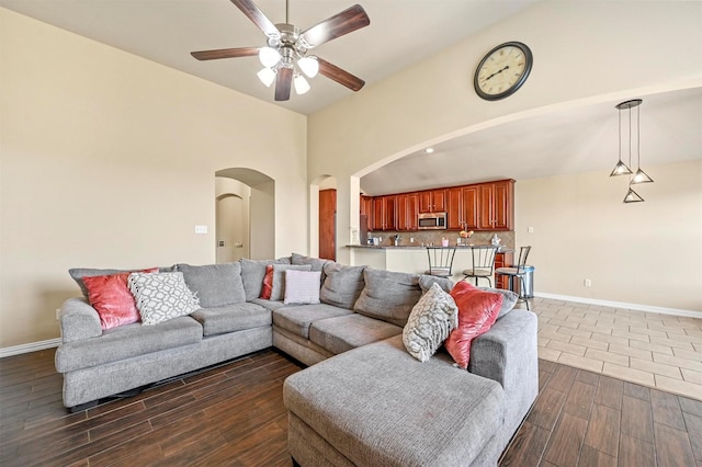 living room featuring ceiling fan, a towering ceiling, and dark hardwood / wood-style floors