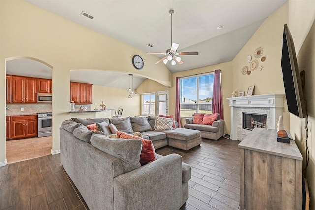 living room with a fireplace, high vaulted ceiling, ceiling fan, and dark wood-type flooring