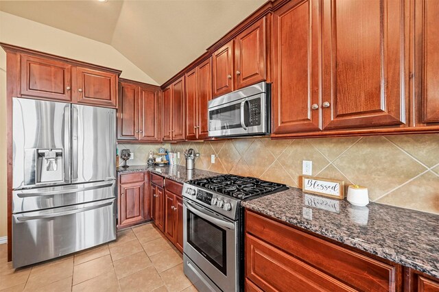 kitchen with stainless steel appliances, backsplash, dark stone countertops, vaulted ceiling, and light tile patterned floors