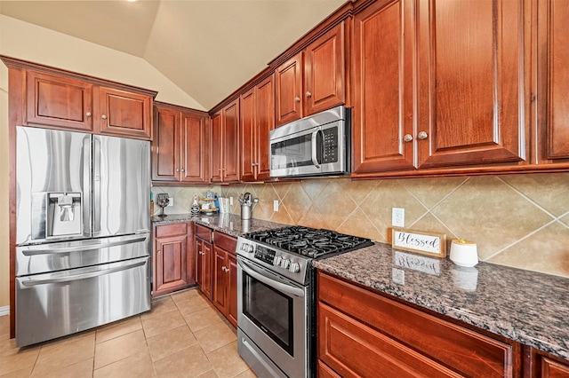 kitchen with light tile patterned floors, stainless steel appliances, tasteful backsplash, vaulted ceiling, and dark stone counters