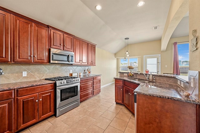 kitchen with dark stone counters, sink, hanging light fixtures, vaulted ceiling, and stainless steel appliances