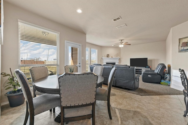 dining room with ceiling fan, light tile patterned flooring, and a textured ceiling