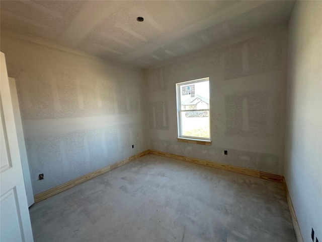 spare room featuring unfinished concrete flooring and baseboards