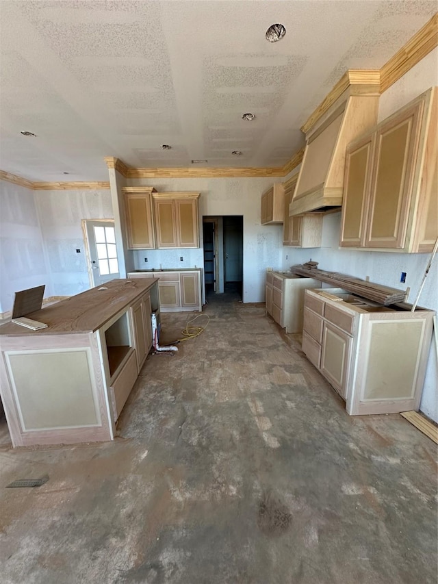 kitchen with premium range hood, a textured ceiling, cream cabinetry, and unfinished concrete flooring