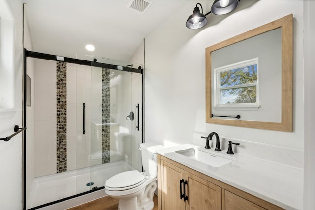 bathroom featuring hardwood / wood-style floors, vanity, toilet, and a shower with shower door