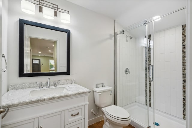 bathroom with toilet, vanity, a shower with shower door, and hardwood / wood-style flooring