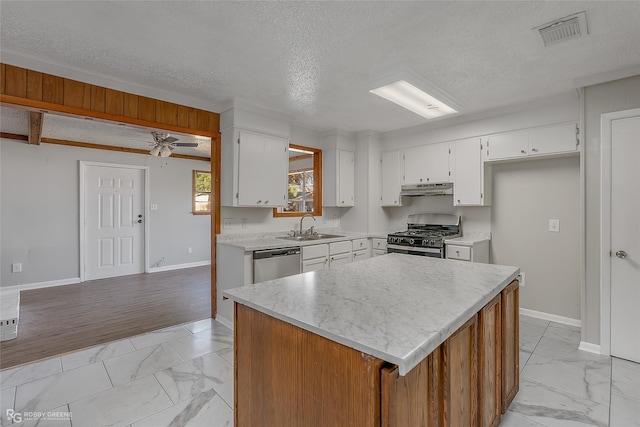 kitchen featuring sink, a textured ceiling, appliances with stainless steel finishes, a kitchen island, and white cabinets