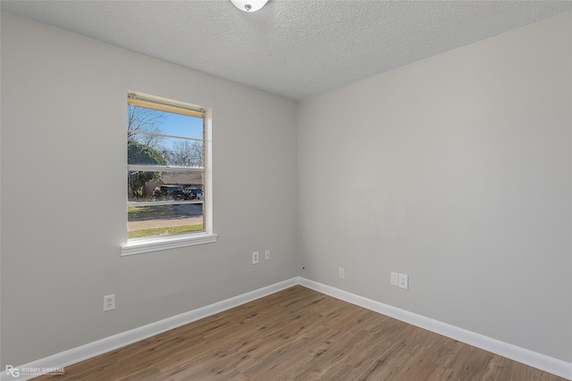 spare room featuring wood-type flooring and a textured ceiling