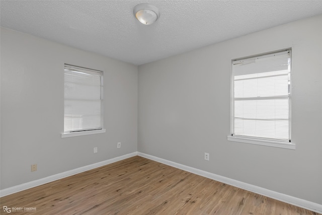 unfurnished room with light hardwood / wood-style floors and a textured ceiling