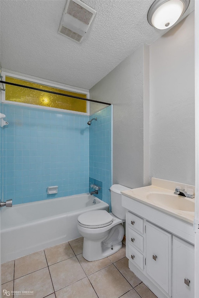 full bathroom featuring vanity, a textured ceiling, tiled shower / bath, tile patterned floors, and toilet