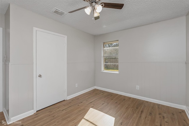 unfurnished room with ceiling fan, light hardwood / wood-style flooring, and a textured ceiling