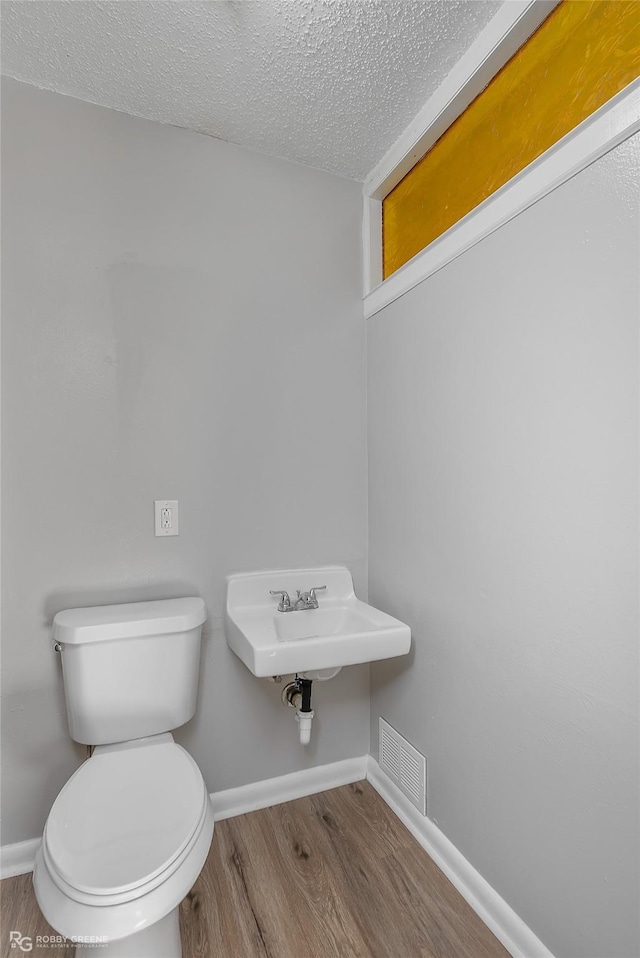 bathroom featuring hardwood / wood-style floors, sink, toilet, and a textured ceiling