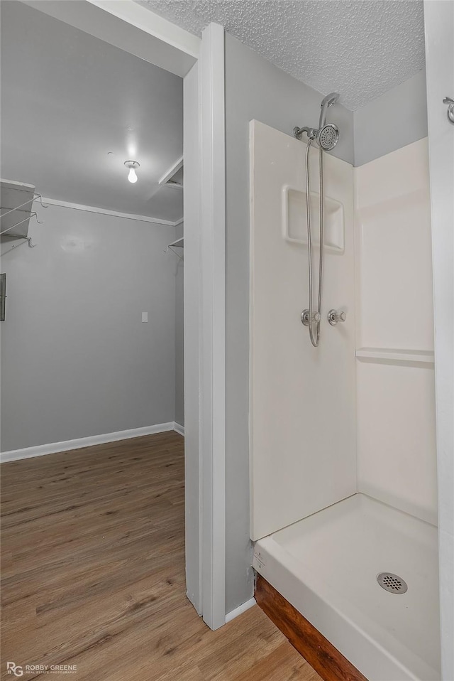 bathroom featuring wood-type flooring, a textured ceiling, and walk in shower