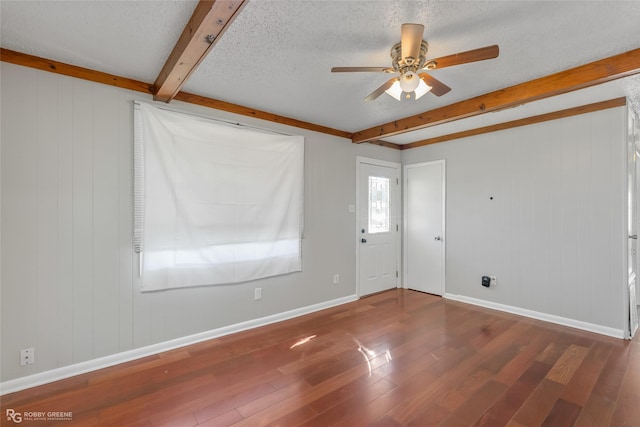 unfurnished room with ceiling fan, dark hardwood / wood-style floors, a textured ceiling, and beam ceiling