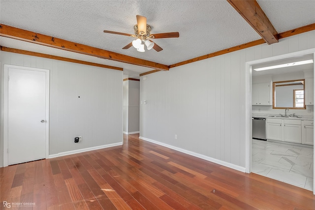 unfurnished room with sink, beam ceiling, a textured ceiling, and light wood-type flooring