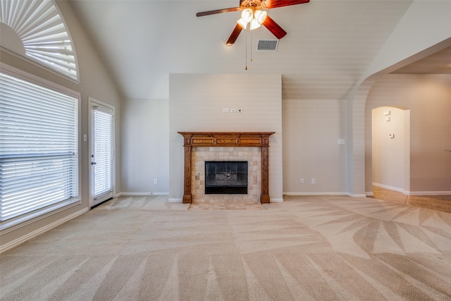 unfurnished living room featuring ceiling fan, light colored carpet, a tile fireplace, and high vaulted ceiling