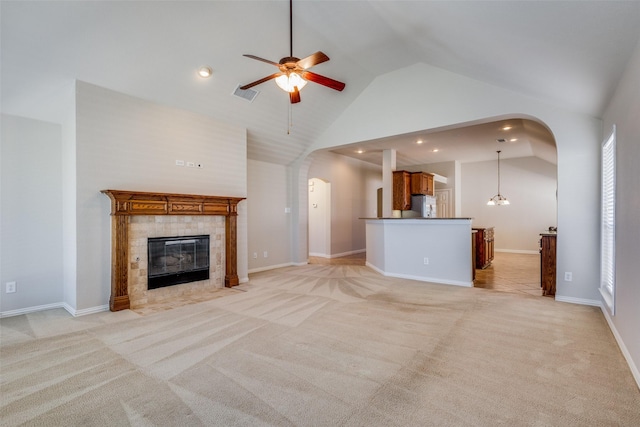 unfurnished living room featuring light carpet, ceiling fan, a healthy amount of sunlight, high vaulted ceiling, and a fireplace