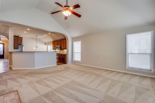 unfurnished living room featuring light carpet, ceiling fan, and high vaulted ceiling