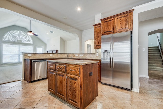 kitchen featuring decorative backsplash, appliances with stainless steel finishes, a center island, and lofted ceiling