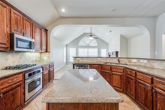 kitchen with sink, stainless steel appliances, tasteful backsplash, vaulted ceiling, and a kitchen island