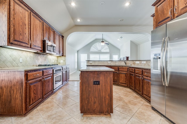 kitchen with a center island, lofted ceiling, backsplash, ceiling fan, and appliances with stainless steel finishes