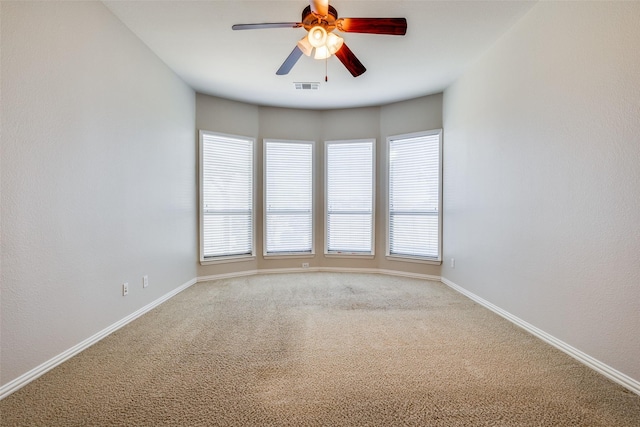 carpeted empty room with ceiling fan and plenty of natural light