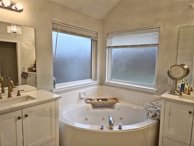 bathroom featuring vanity, a bathtub, a wealth of natural light, and vaulted ceiling